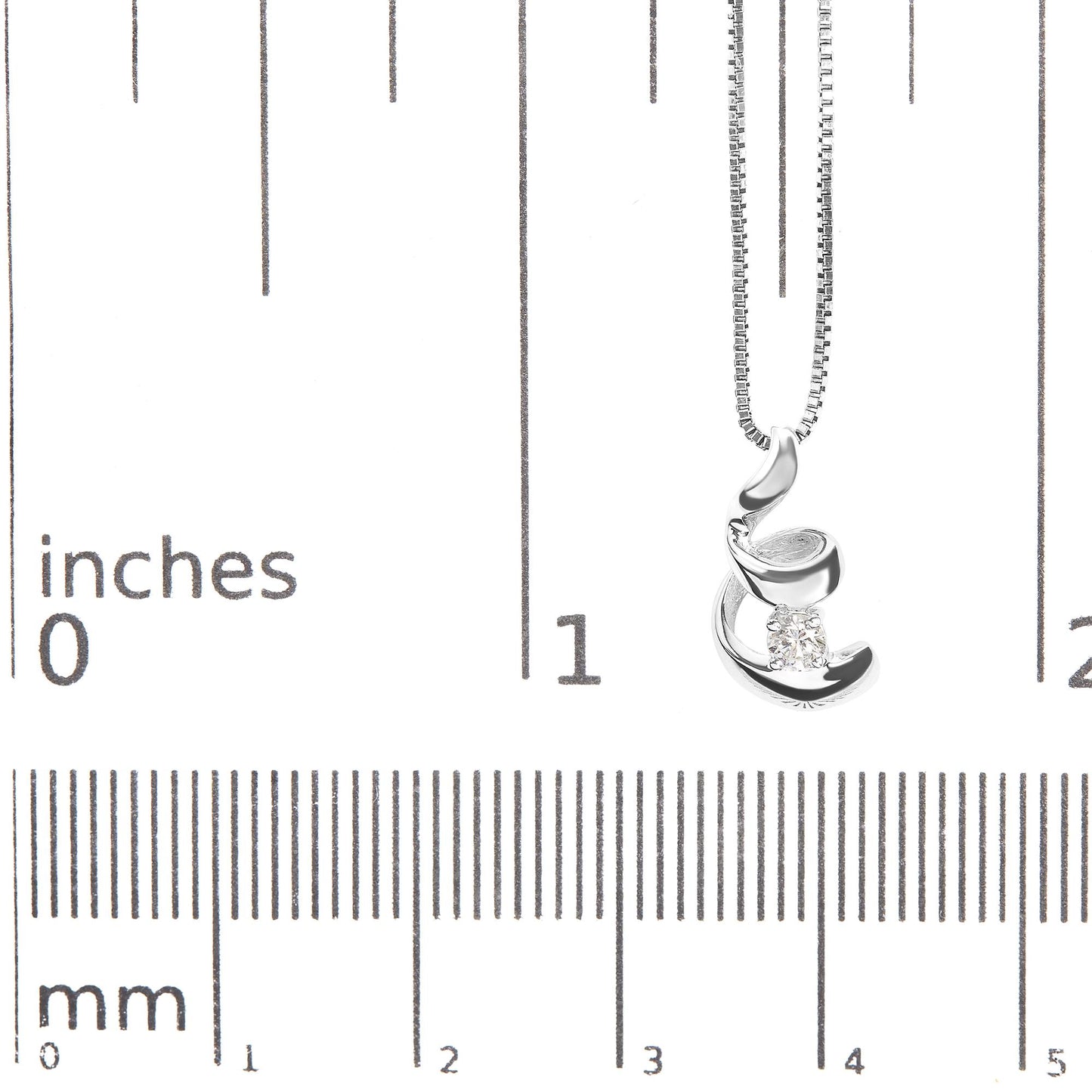 Close-up of a white metal necklace with a curved abstract pendant holding a round white gemstone, displayed on a ruler for size reference.