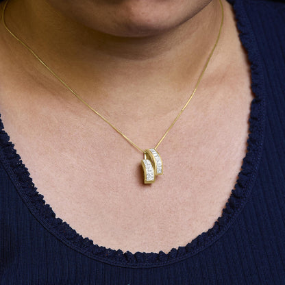 Yellow metal necklace with two curved pendants set with white baguette and princess-shaped gemstones, shown close-up on a model's neck.