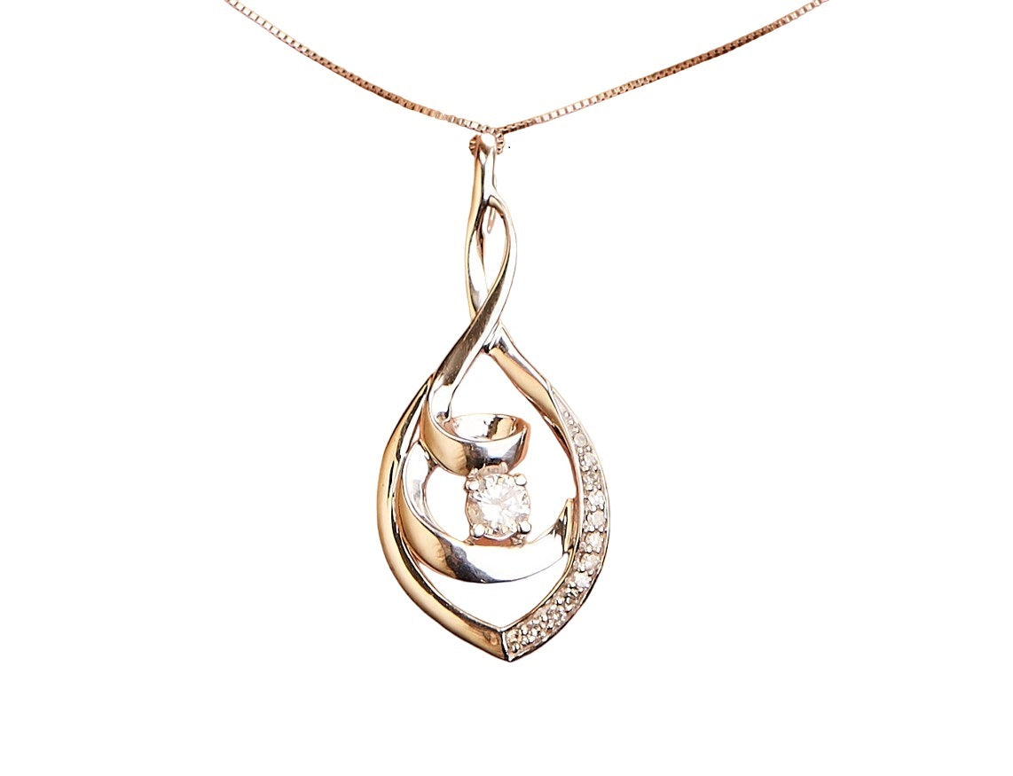 Close-up front angle of a white metal necklace with a pendant featuring one central round white gemstone and additional smaller round white gemstones along one side of the pendant's swirl design.