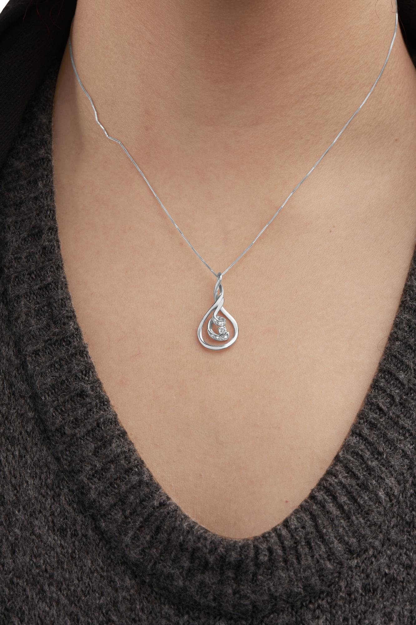White metal necklace with a pendant featuring a teardrop shape and white gemstones, shown on a model from the front angle.