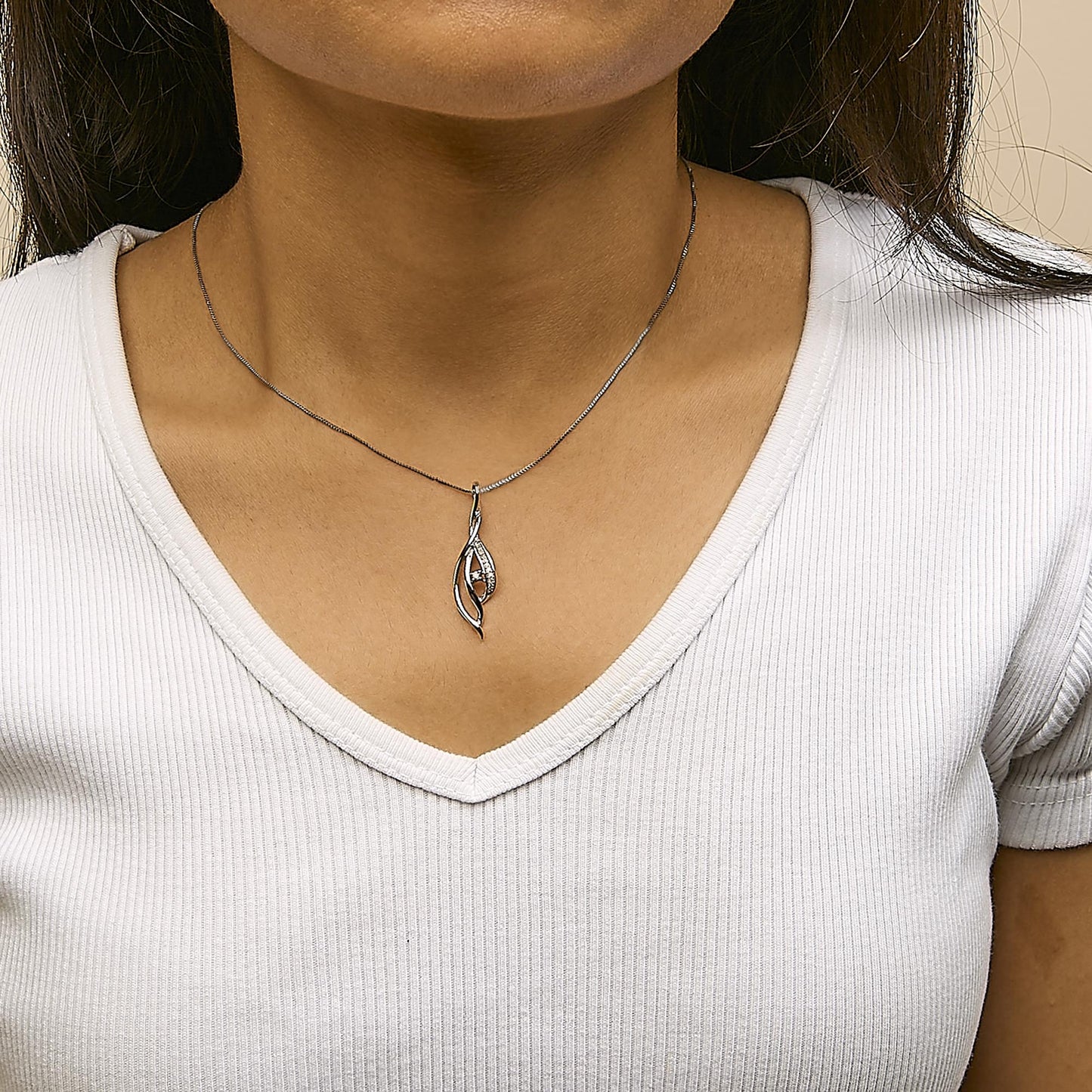 White metal necklace with an abstract pendant featuring one larger round white gemstone and a row of smaller round white gemstones, worn on a model, front-facing angle.