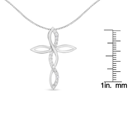 Front view of a white metal cross-shaped necklace pendant with a twisted design featuring round white gemstones in prong settings, shown with a ruler for size reference.