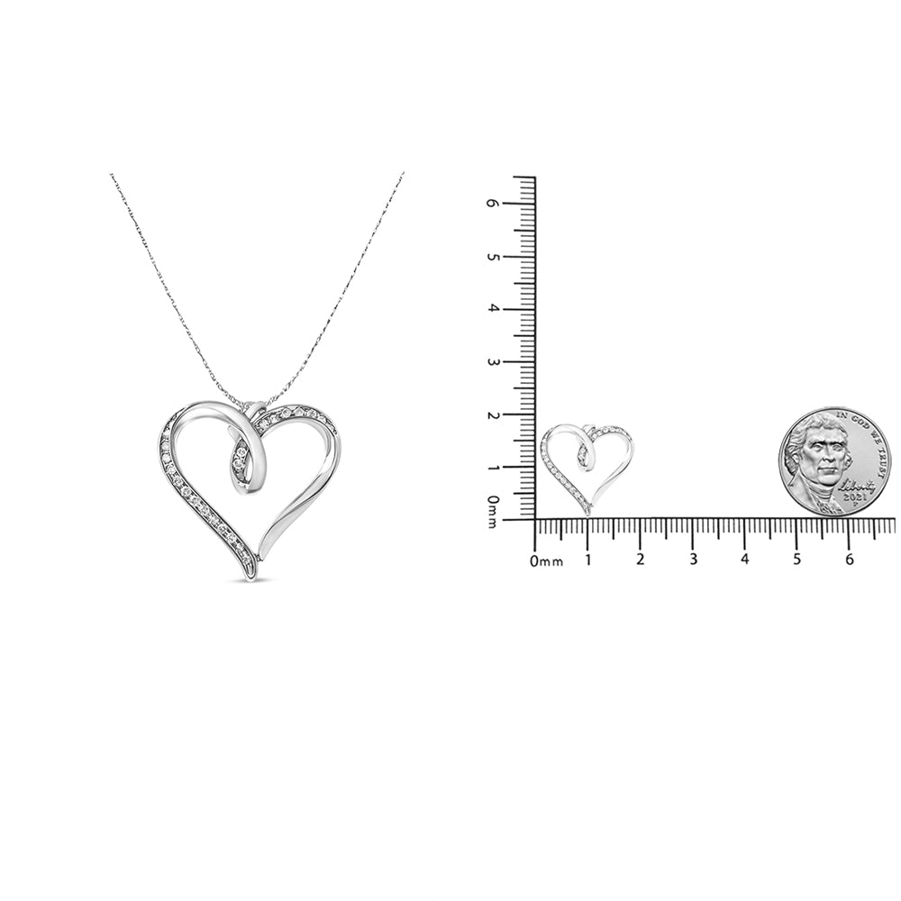 White metal heart-shaped necklace with round white gemstones in prong settings, shown from front angle on a chain, alongside a close-up of the pendant placed on a ruler with a coin for size reference.