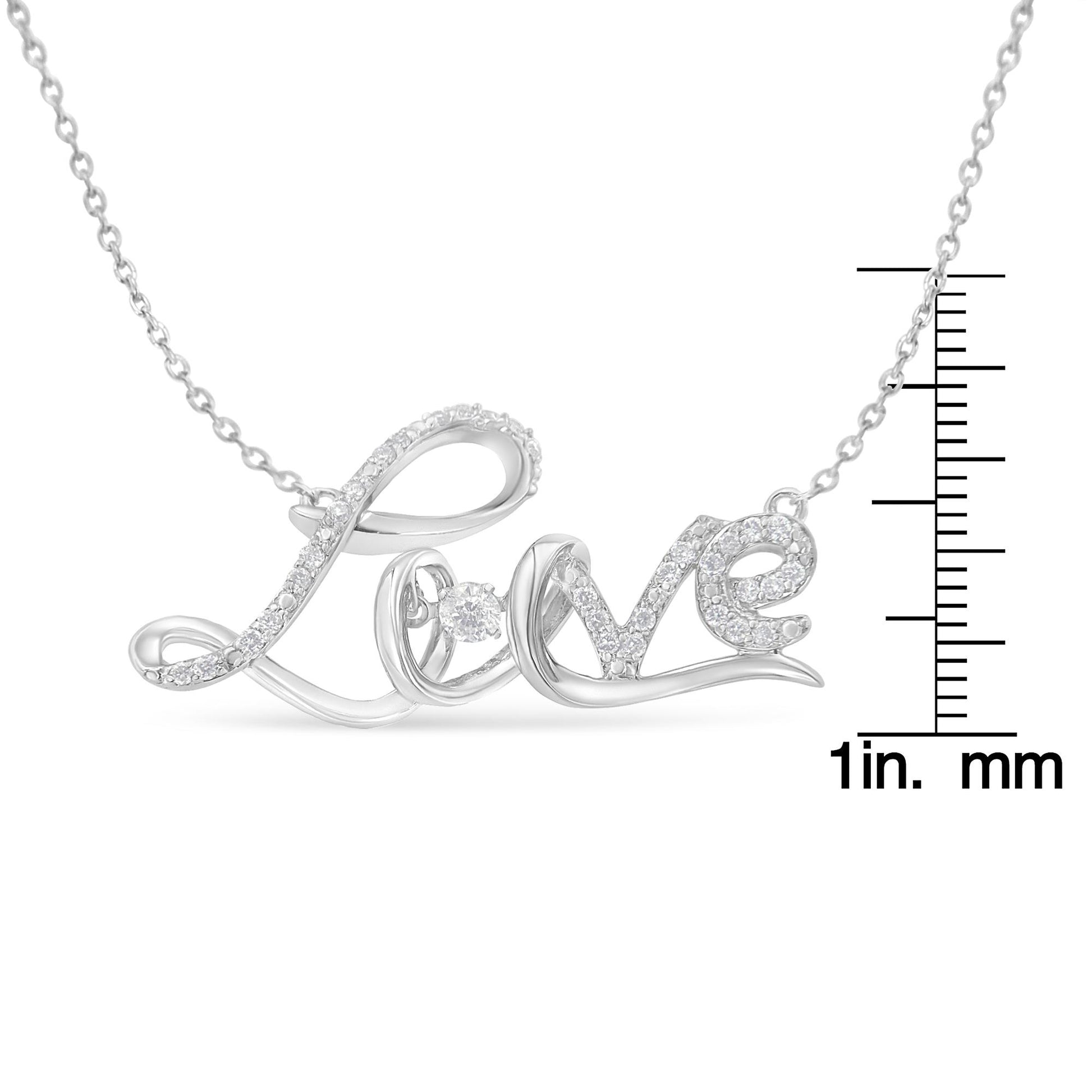 White metal necklace pendant spelling 'Love' with white gemstones in prong settings, photographed from the front on a ruler for size reference.