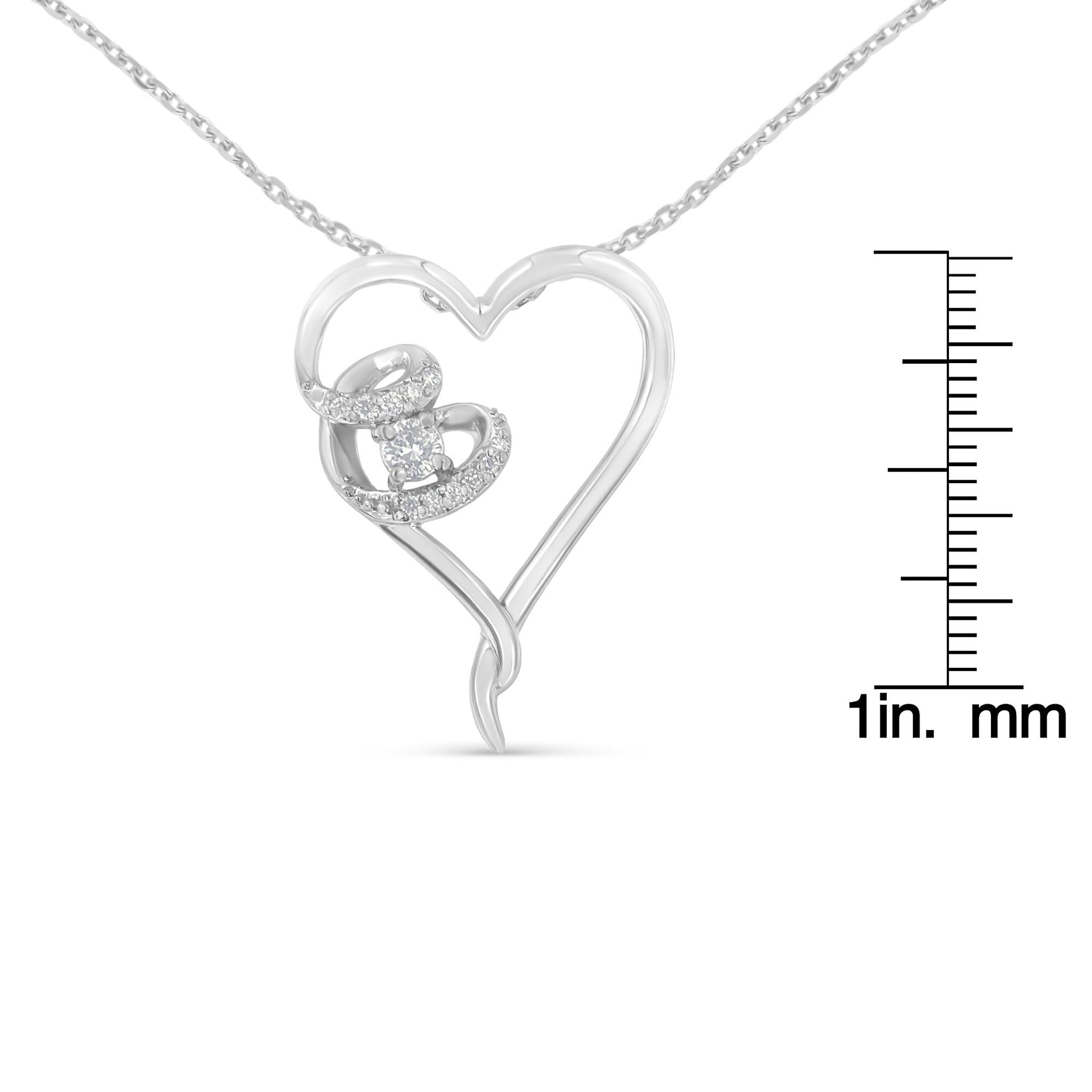 Close-up front view of a white metal heart-shaped necklace pendant with a swirl design adorned with round white gemstones, shown next to a ruler for size reference.
