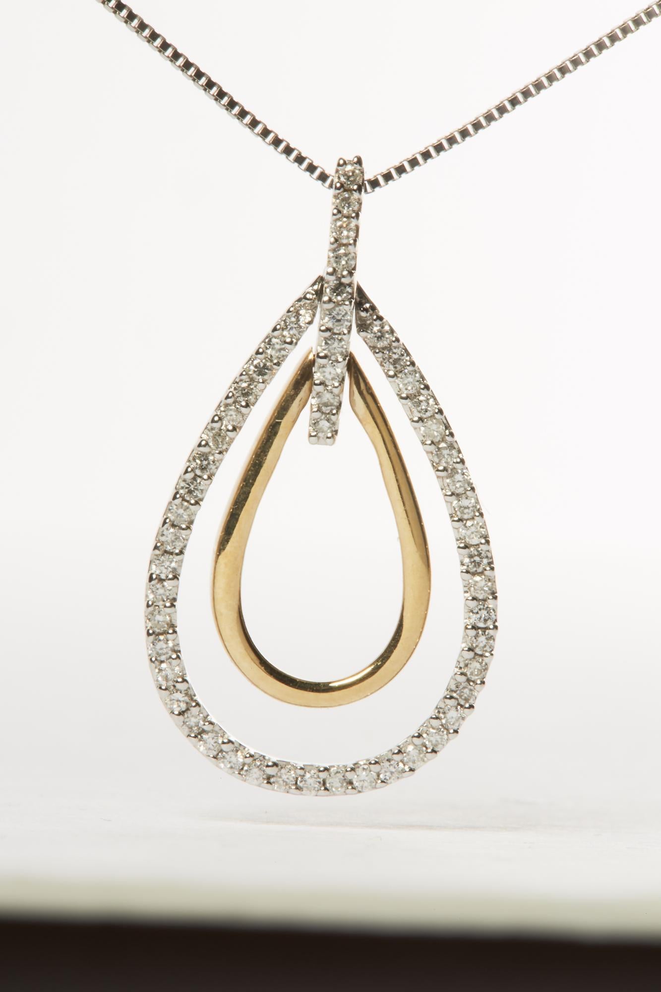 Close-up front view of a two-toned teardrop-shaped necklace pendant with an inner smooth gold-colored loop and an outer loop adorned with small white round gemstones in prong settings, suspended on a chain.