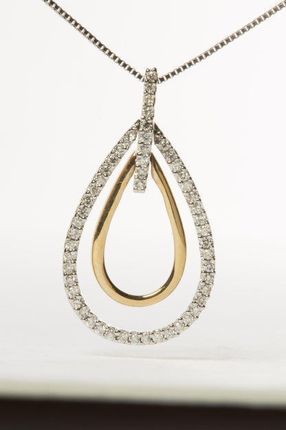 Close-up front view of a two-toned teardrop-shaped necklace pendant with an inner smooth gold-colored loop and an outer loop adorned with small white round gemstones in prong settings, suspended on a chain.