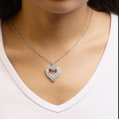 White metal heart-shaped necklace with round prong-set white gemstones and baguette channel-set white gemstones, shown on a model from the front angle.