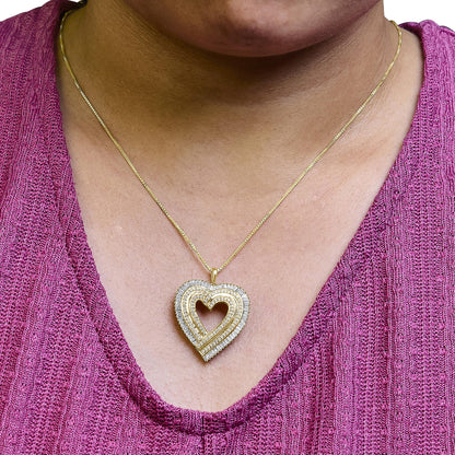 Close-up front view of a yellow metal heart-shaped pendant necklace worn on a model, featuring white round prong-set gemstones and white baguette channel-set gemstones.