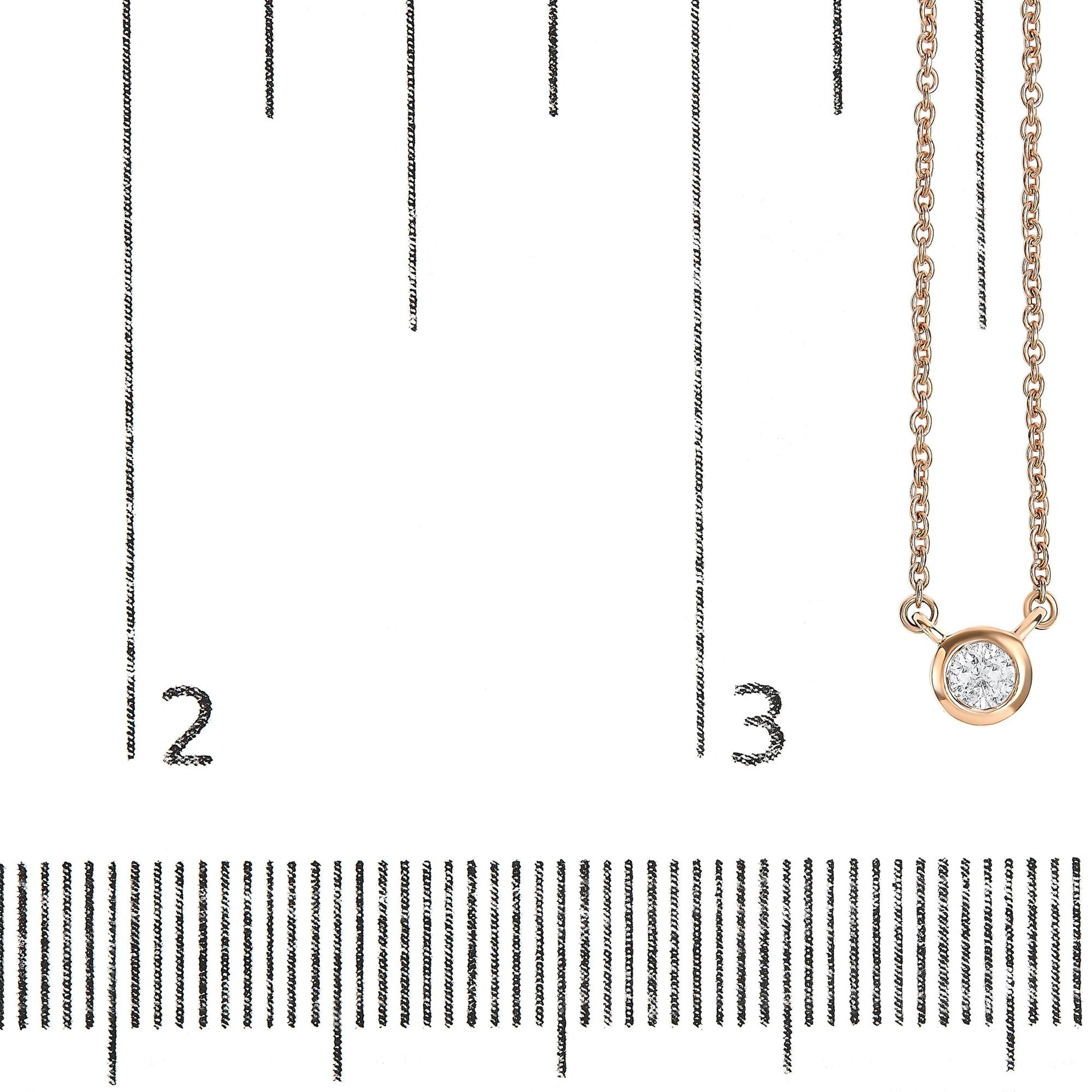 Rose metal necklace with a round white gemstone in bezel setting, shown hanging on a ruler for size reference, front view.