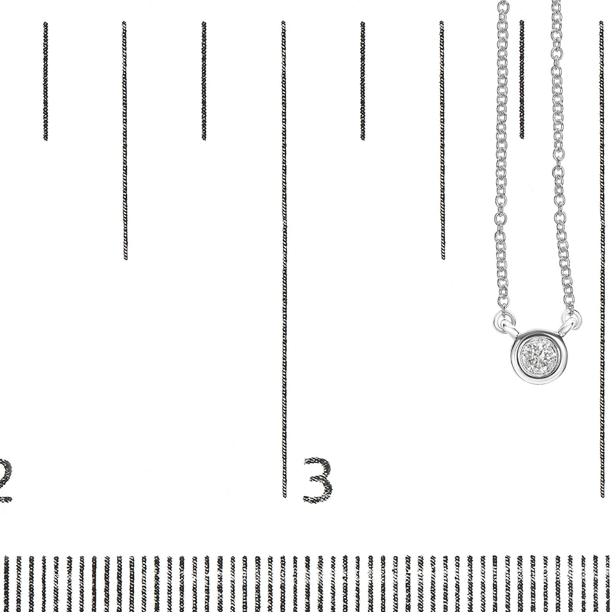 Close-up front angle of a white metal necklace with a single round bezel-set white gemstone pendant, displayed on a ruler for size reference.