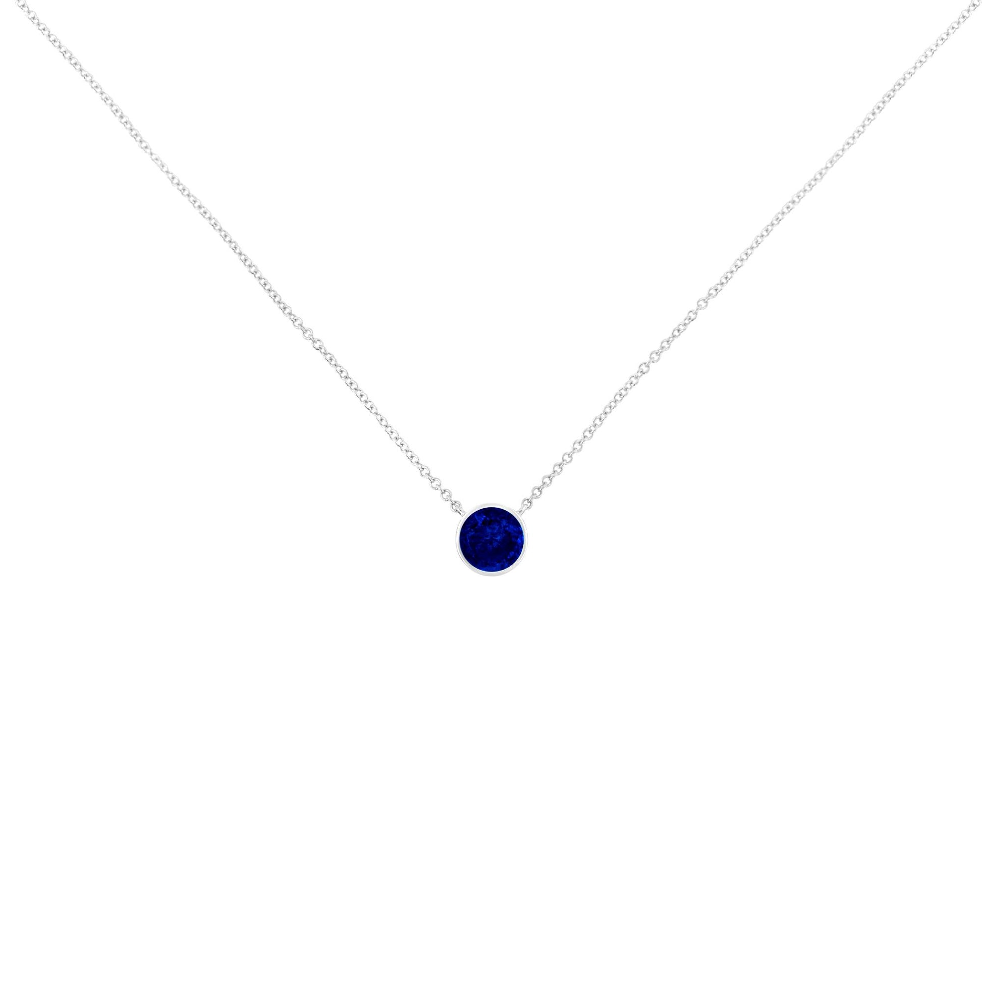 Close-up front view of a white metal necklace with a single round blue gemstone in a bezel setting.