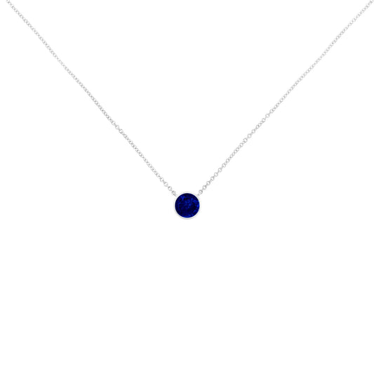 Close-up front view of a white metal necklace with a single round blue gemstone in a bezel setting.