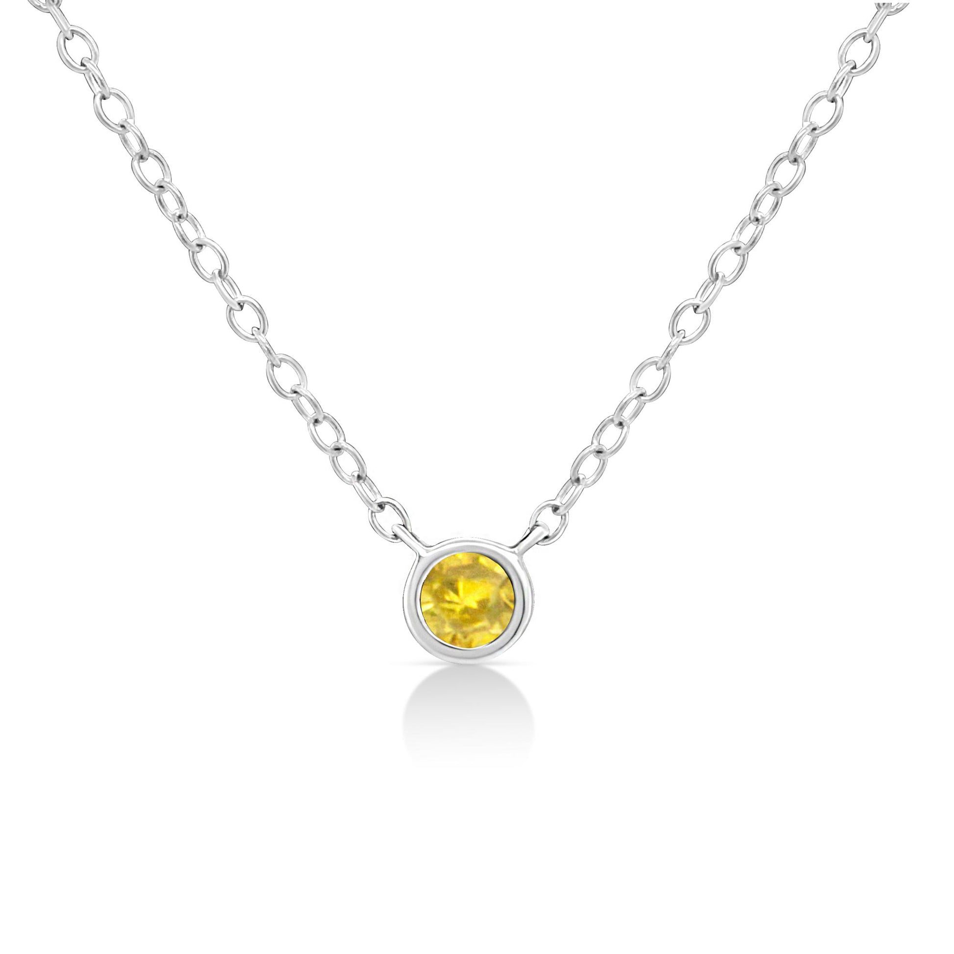 Front-facing shot of a white metal necklace with a round, bezel-set yellow gemstone pendant.