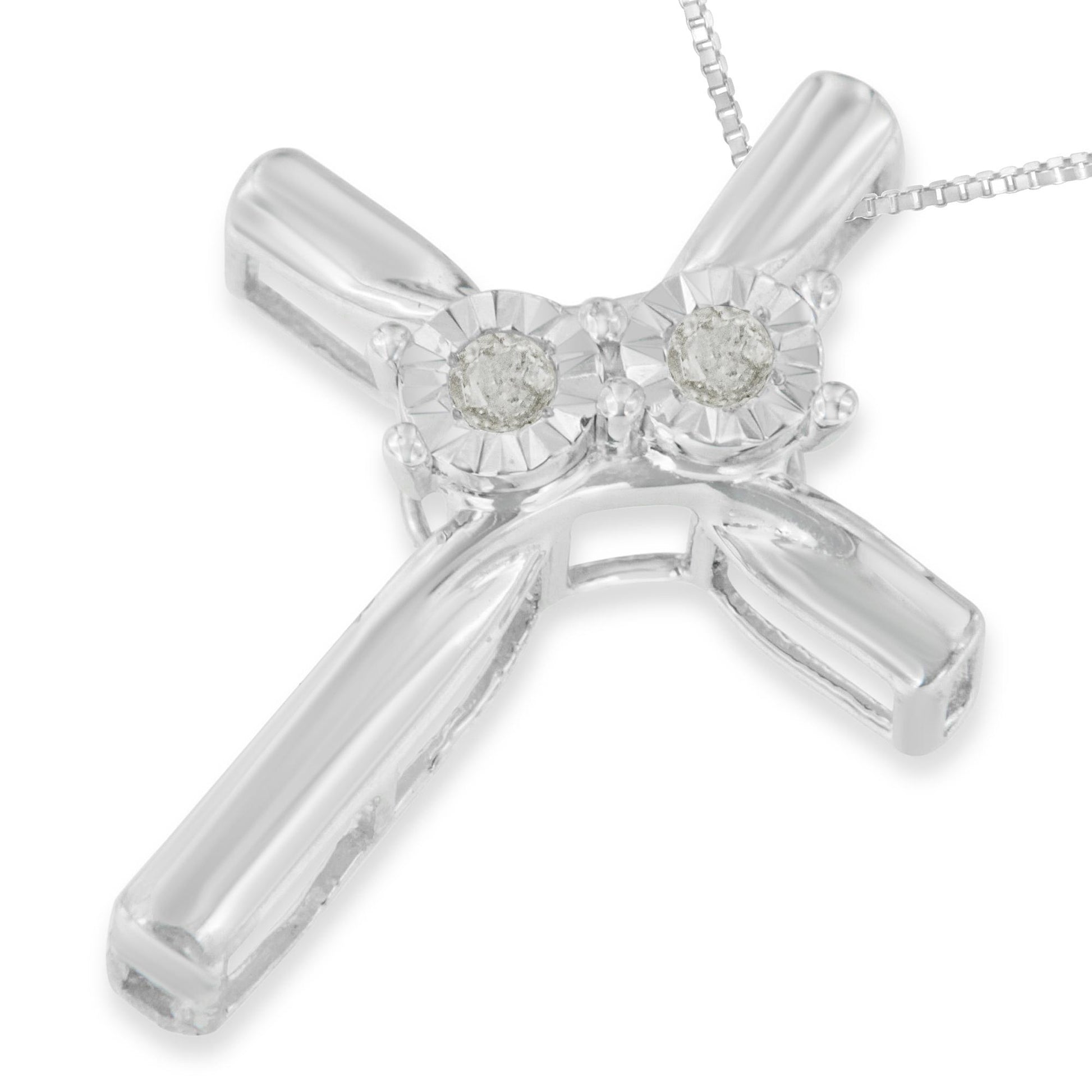 Close-up front angle of a white metal cross necklace pendant with two round white gemstones in miracle settings at the top, attached to a fine chain.