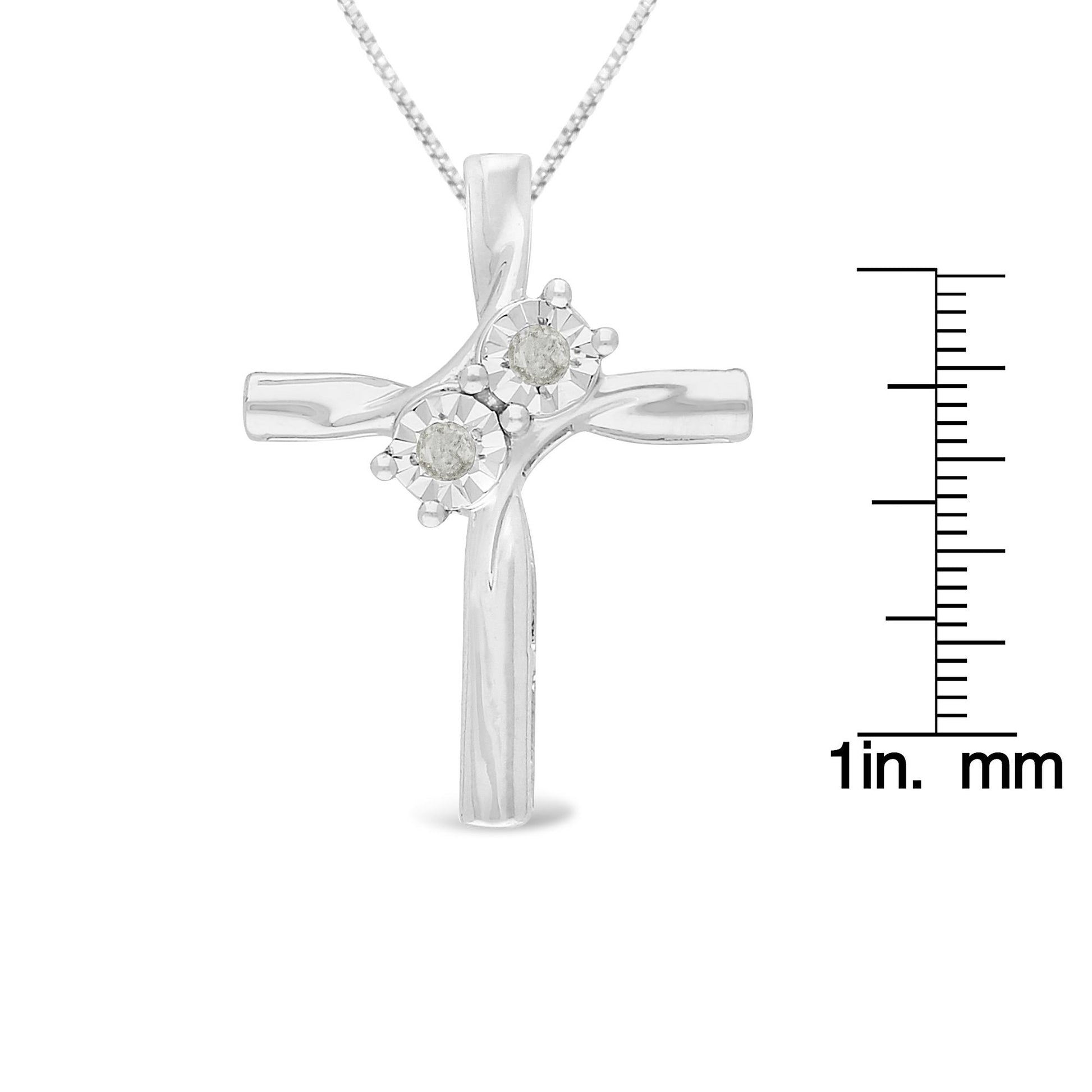 Front view of a white metal cross necklace with two round white gemstones in miracle settings, displayed next to a ruler for size reference.