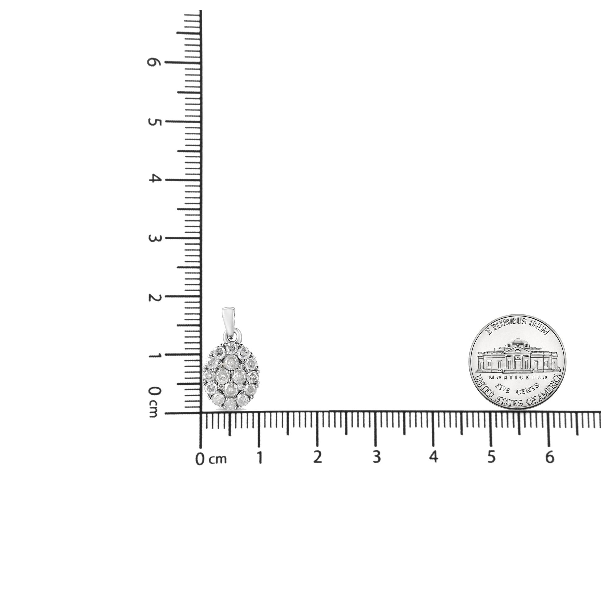 White necklace pendant with multiple round white gemstones in prong settings, photographed on a ruler and next to a coin for size reference, front view.