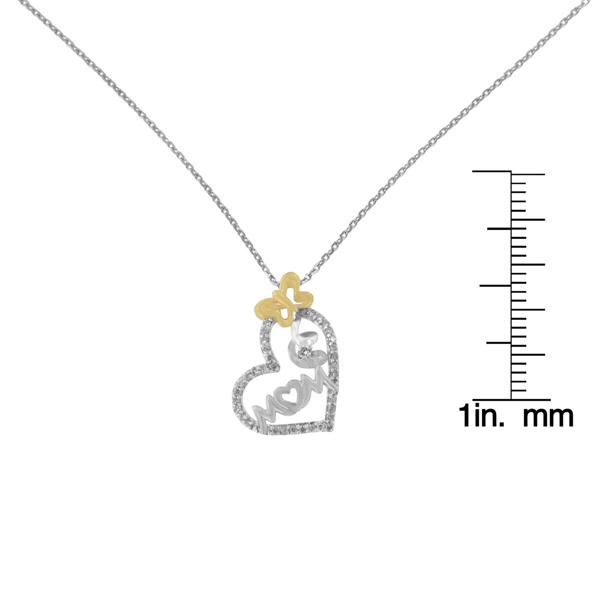 Front view of a white and rose metal necklace with a heart-shaped pendant outlined with small white gemstones. The word 'MOM' is incorporated inside the heart, and there is a small rose-colored butterfly detail at the top of the pendant. The necklace is displayed against a white background with a ruler for size reference.