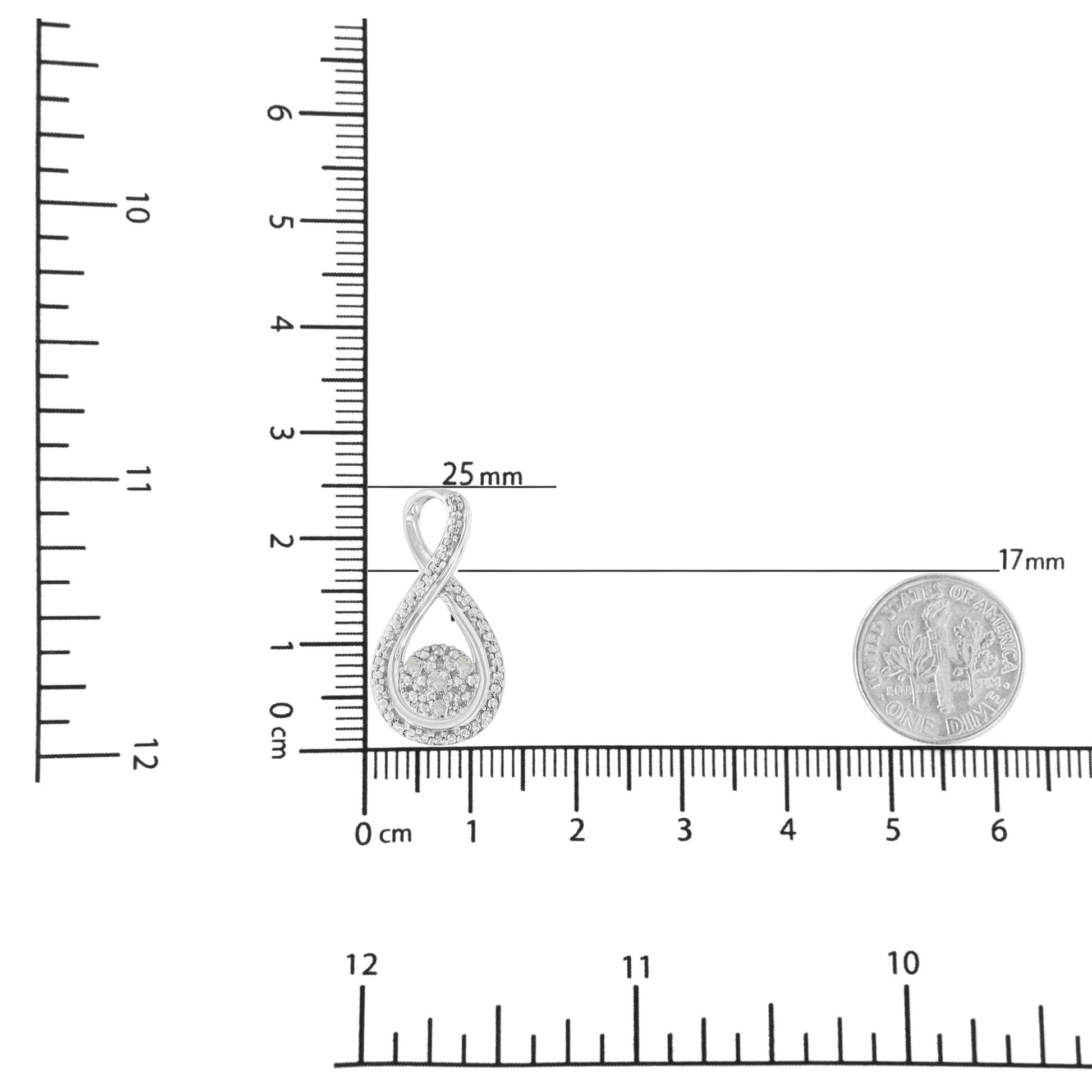 Close-up of a white metal infinity-shaped necklace pendant with white round gemstones in prong settings, displayed on a ruler and next to a coin for size reference.