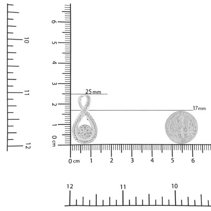 Close-up of a white metal infinity-shaped necklace pendant with white round gemstones in prong settings, displayed on a ruler and next to a coin for size reference.