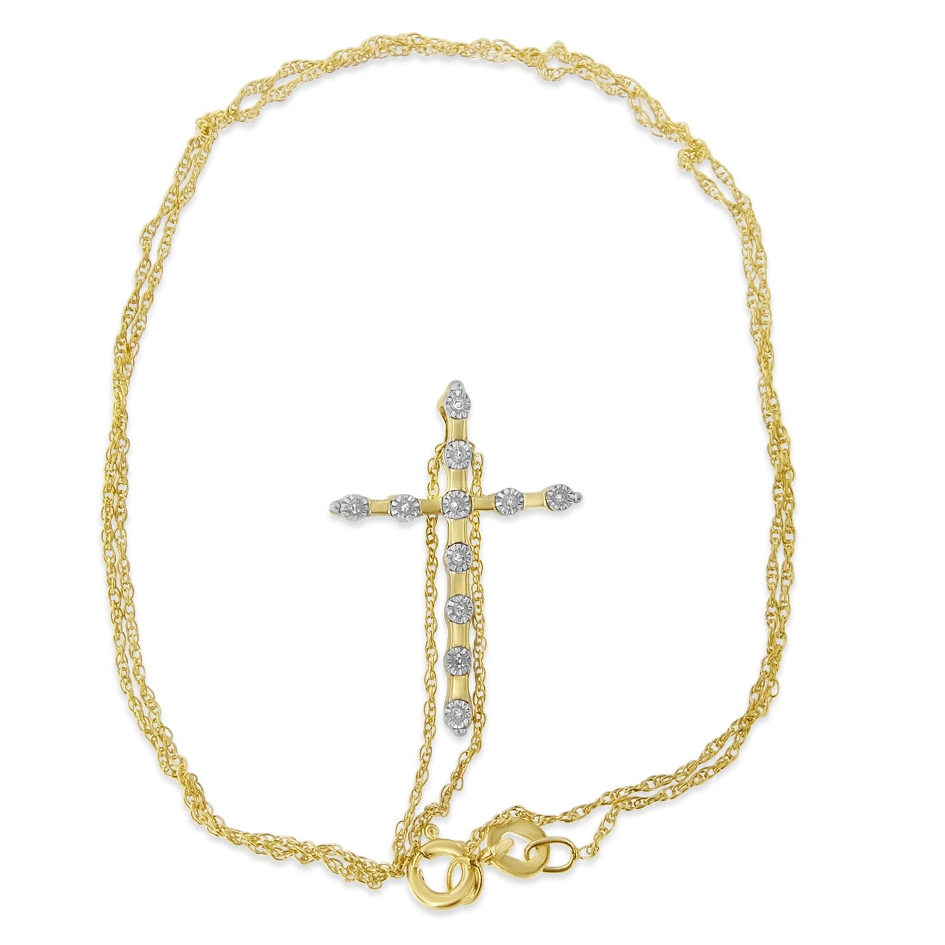 Yellow metal necklace with a cross-shaped pendant featuring round white gemstones in a miracle setting, shot from above.
