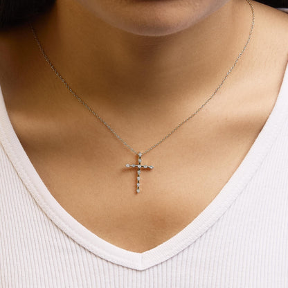 Close-up shot of a yellow metal necklace on a model, featuring a cross pendant set with round white gemstones in a miracle setting.