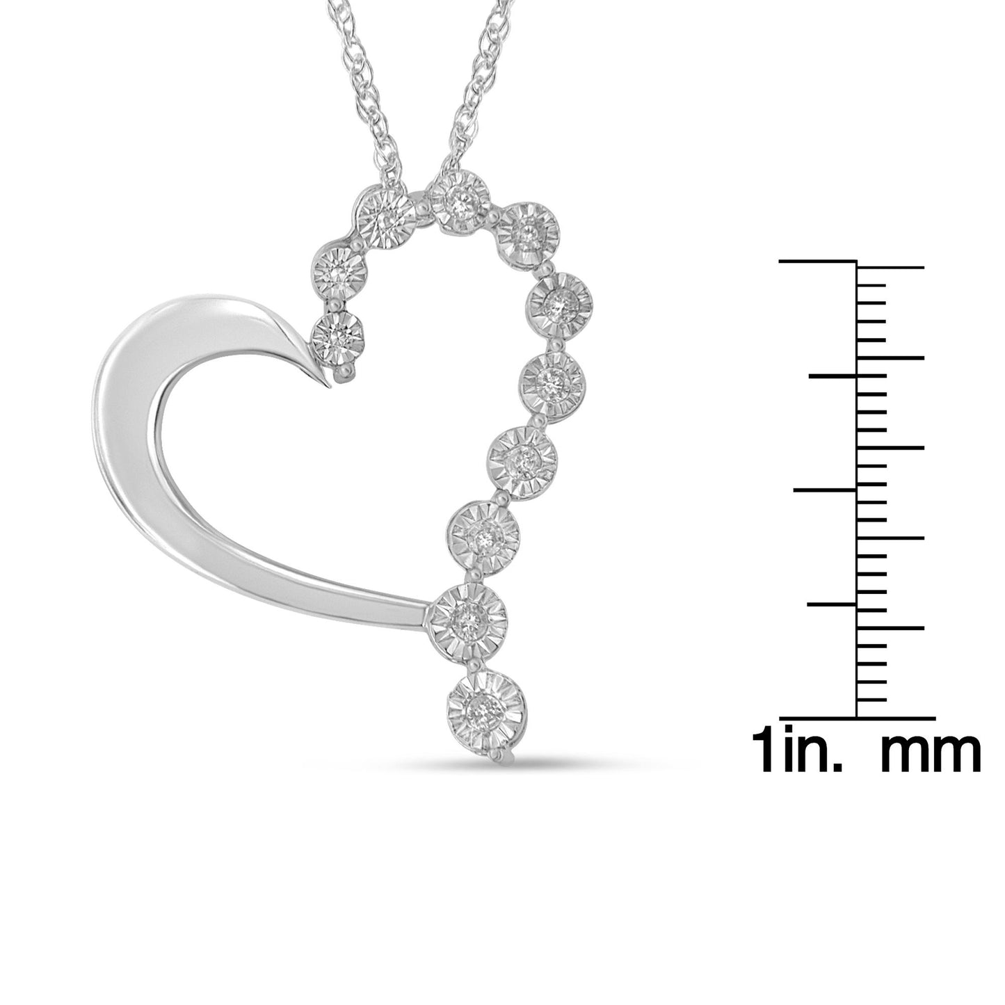 Close-up front view of a white metal heart-shaped necklace pendant with round white gemstones in miracle settings along one side, shown next to a ruler for size reference.