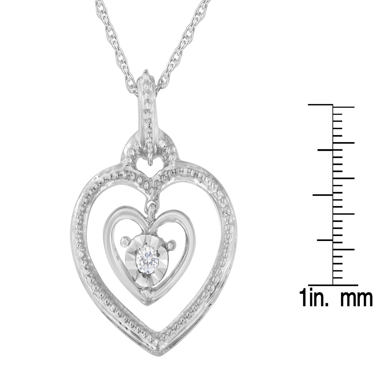 Front angle of white metal heart-shaped necklace pendant with an inner heart featuring a single round white gemstone, shown next to a ruler for size reference.