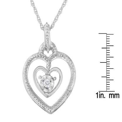 Front angle of white metal heart-shaped necklace pendant with an inner heart featuring a single round white gemstone, shown next to a ruler for size reference.