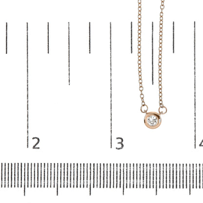 Close-up front view of a rose metal necklace with a round white gemstone in bezel setting, displayed on a ruler for size reference.