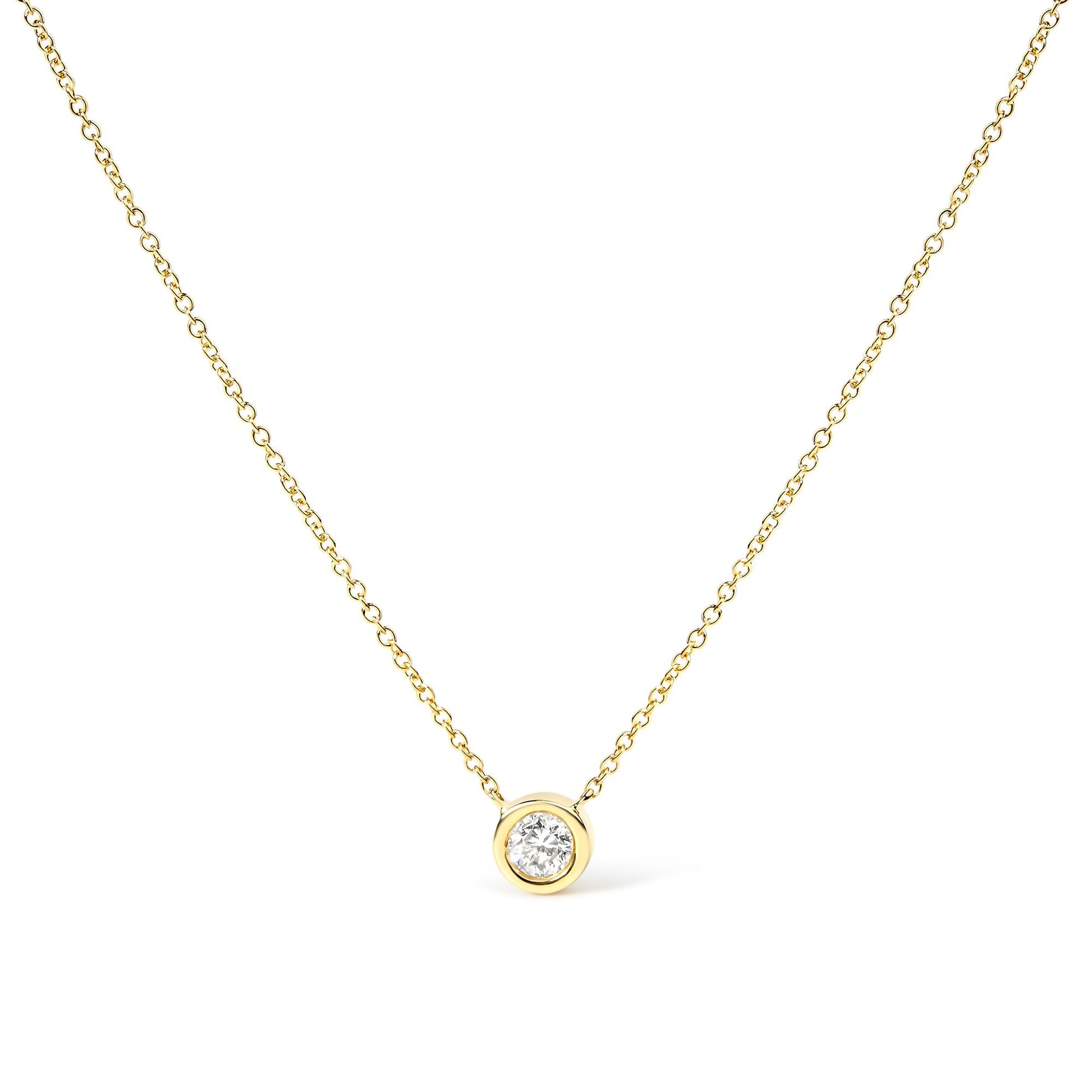 Front-facing close-up of a yellow metal necklace with a single round white gemstone in bezel setting pendant.