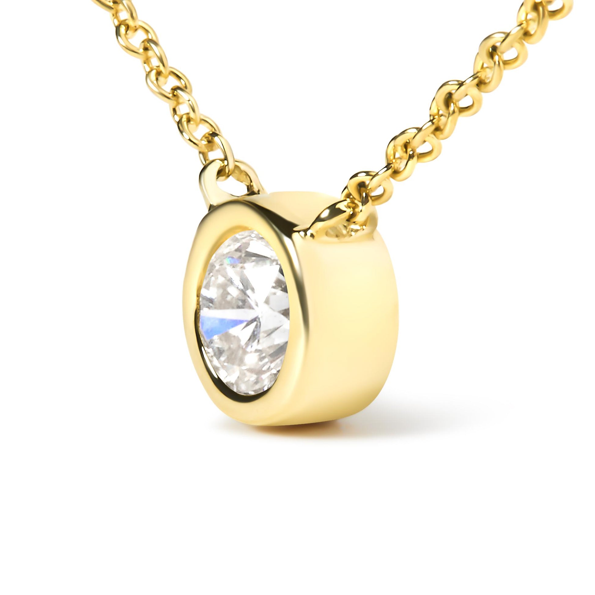 Close-up front angle of a yellow metal necklace with a round white gemstone in a bezel setting pendant.