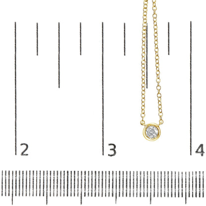 Close-up front view of a yellow metal necklace with a round white gemstone in bezel setting, displayed on a ruler for size reference.