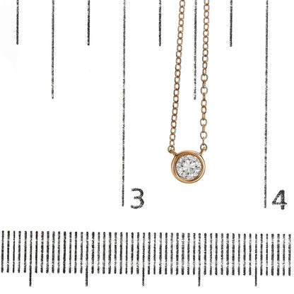 Rose-colored necklace with a round white gemstone in a bezel setting, photographed from the front on a ruler for size reference.