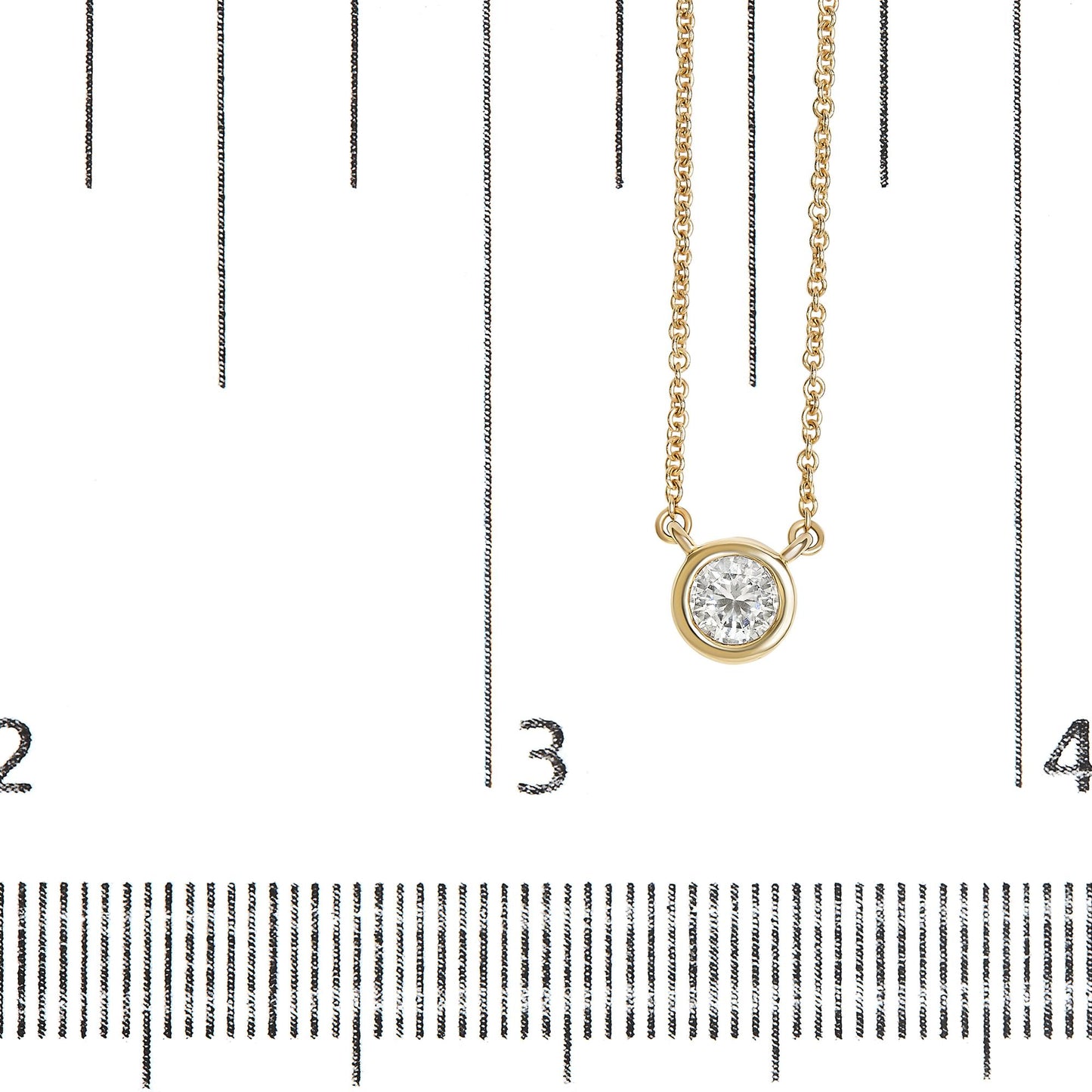 Close-up front view of a yellow metal necklace with a round white gemstone in bezel setting, displayed on a ruler for size reference.