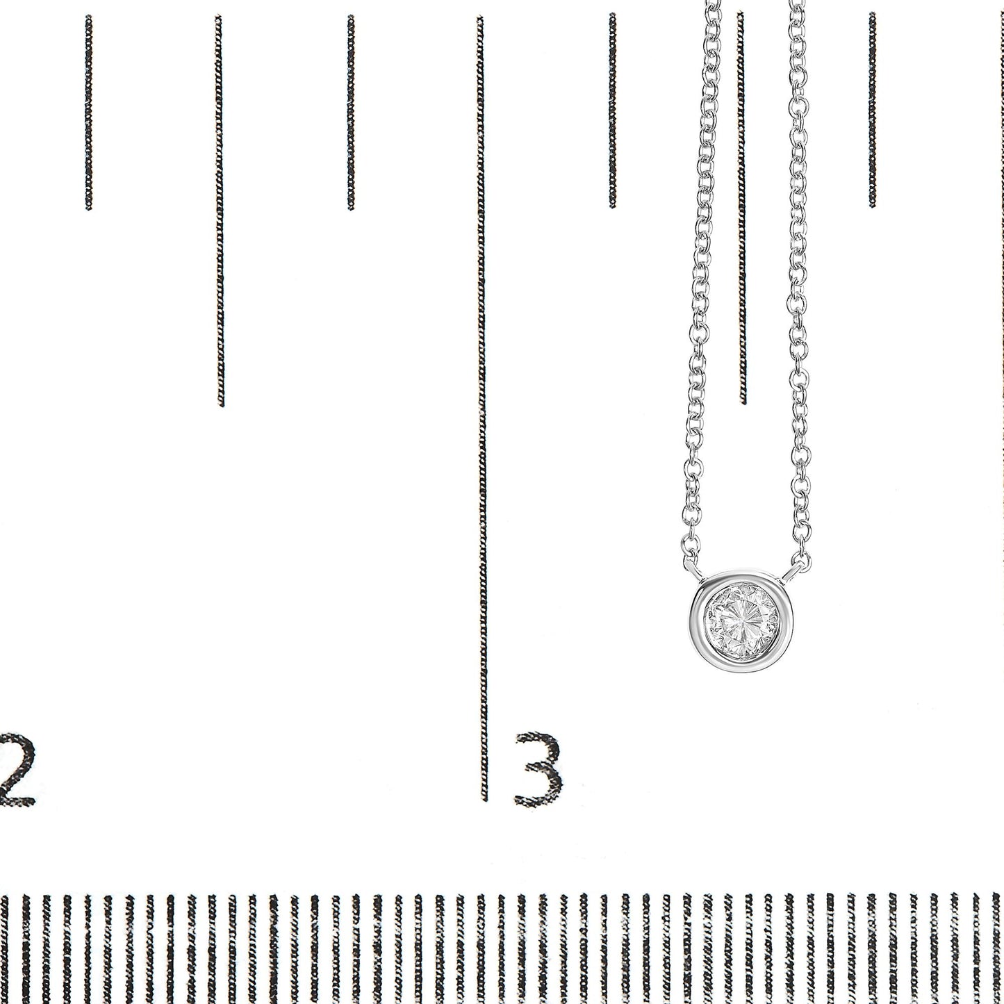 Close-up image of a white metal necklace with a round bezel-set white gemstone pendant, shown on a ruler for size reference from a front angle.
