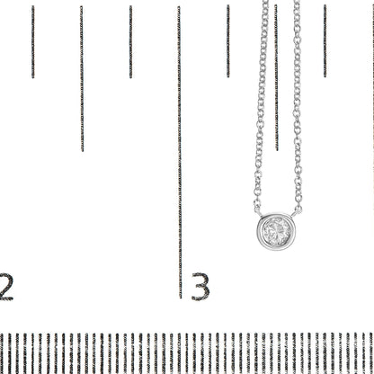 Close-up image of a white metal necklace with a round bezel-set white gemstone pendant, shown on a ruler for size reference from a front angle.