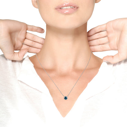 White necklace with a round blue gemstone in bezel setting, worn on a model, front angle.