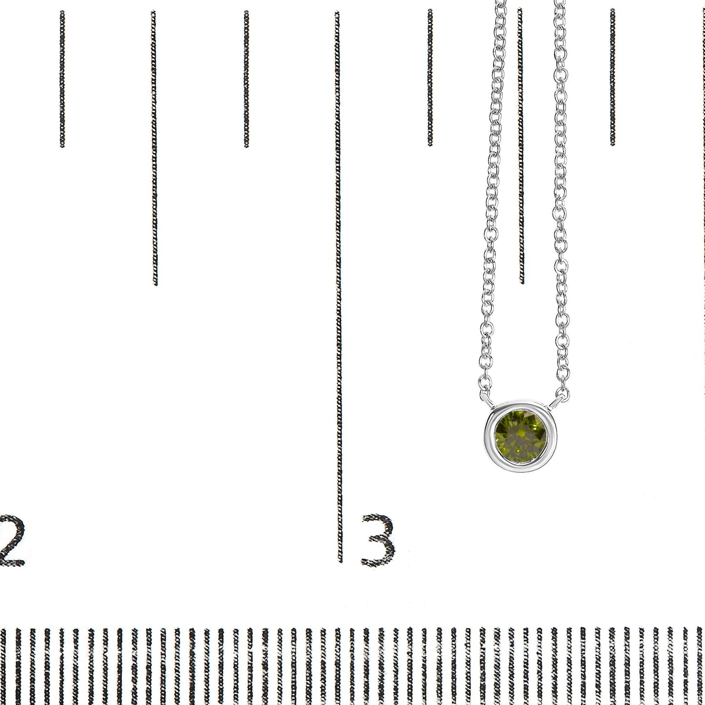 Close-up front view of a white metal necklace with a round green gemstone in a bezel setting, displayed on a ruler for size reference.