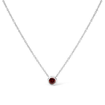 Front-facing shot of a white metal necklace with a round red gemstone in a bezel setting pendant.