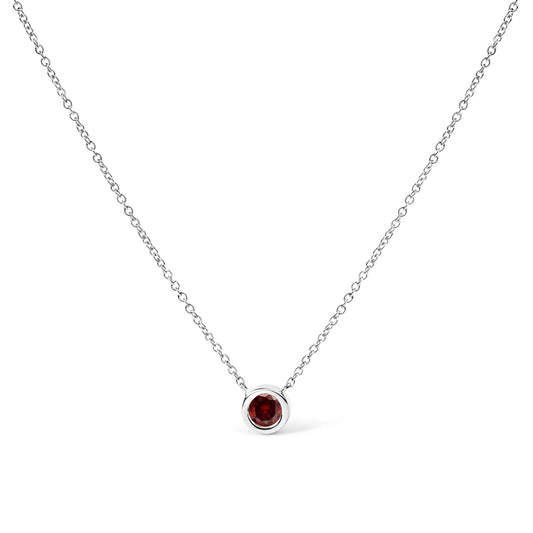 Front-facing shot of a white metal necklace with a round red gemstone in a bezel setting pendant.