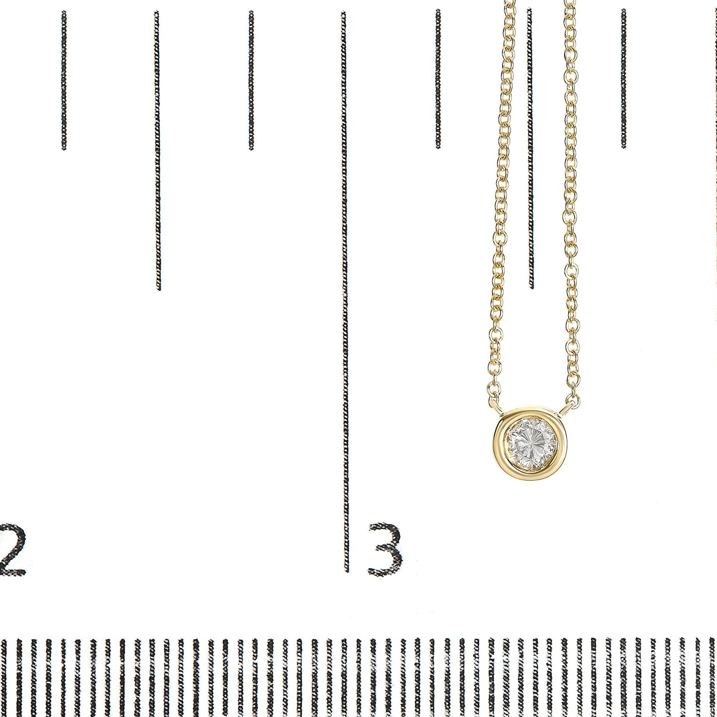 Close-up front angle of a yellow metal necklace with a round white gemstone in bezel setting, displayed on a ruler for size reference.