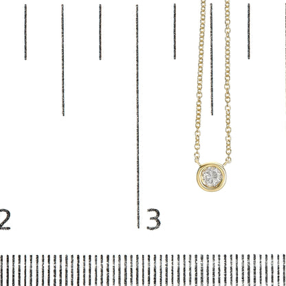 Close-up front angle of a yellow metal necklace with a round white gemstone in bezel setting, displayed on a ruler for size reference.