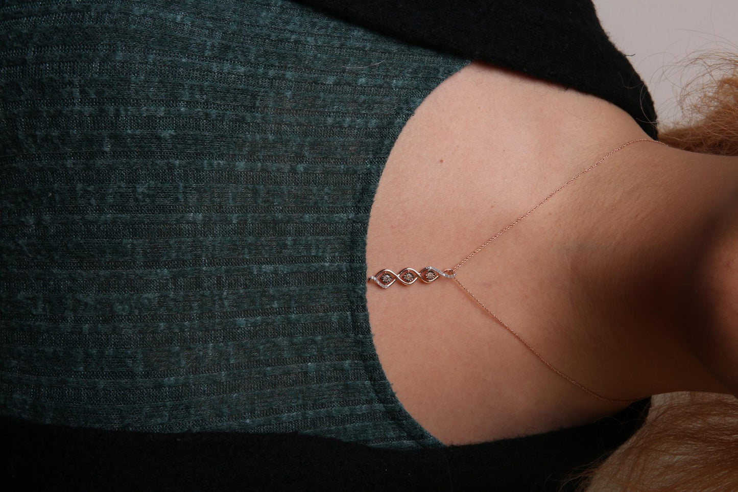 Close-up front view of a two-toned necklace with a pendant featuring three champagne-colored round gemstones in a miracle setting and multiple white round gemstones in prong settings, worn on a model.
