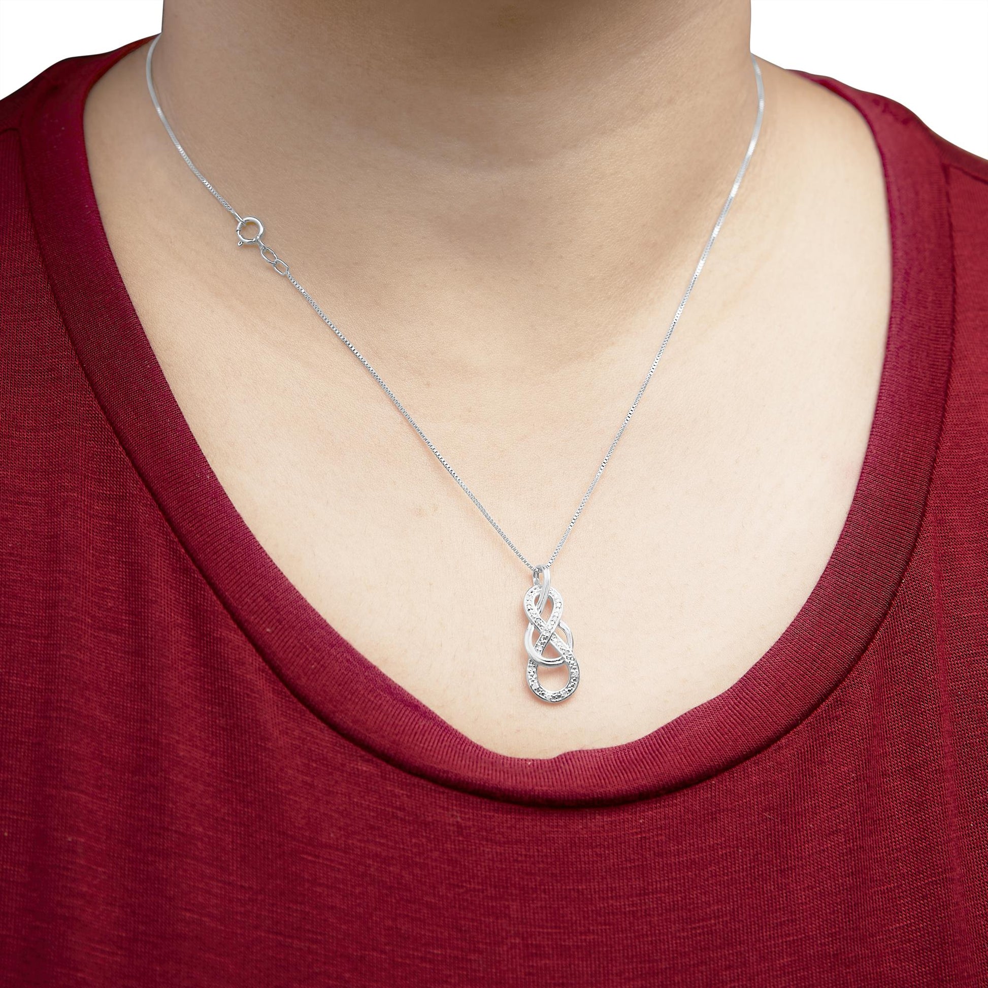 White metal necklace with an intertwined loop pendant set with round white gemstones, worn on a model, front view.