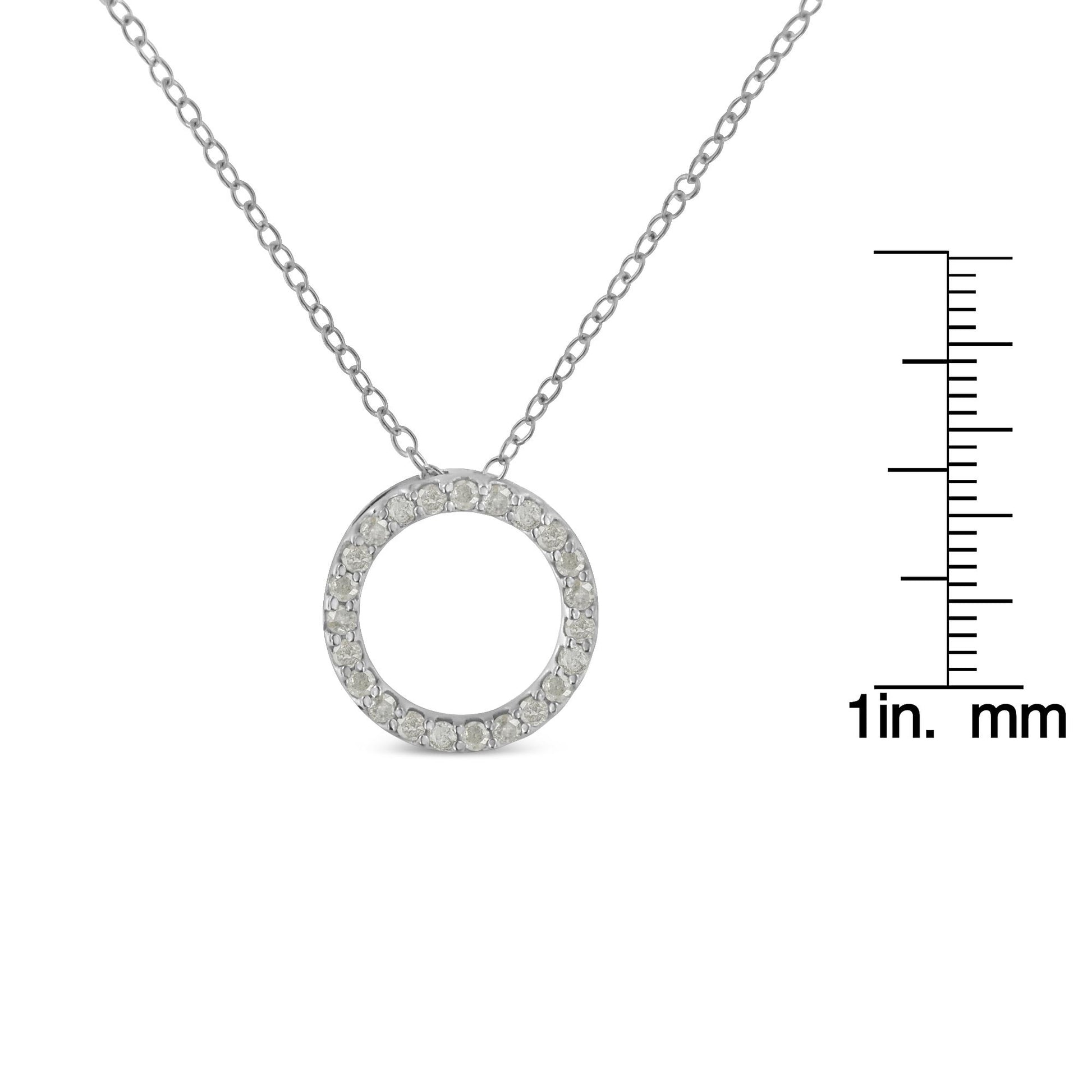 Front-facing shot of a white metal circular necklace pendant with round white gemstones in prong settings, shown next to a ruler for size reference.