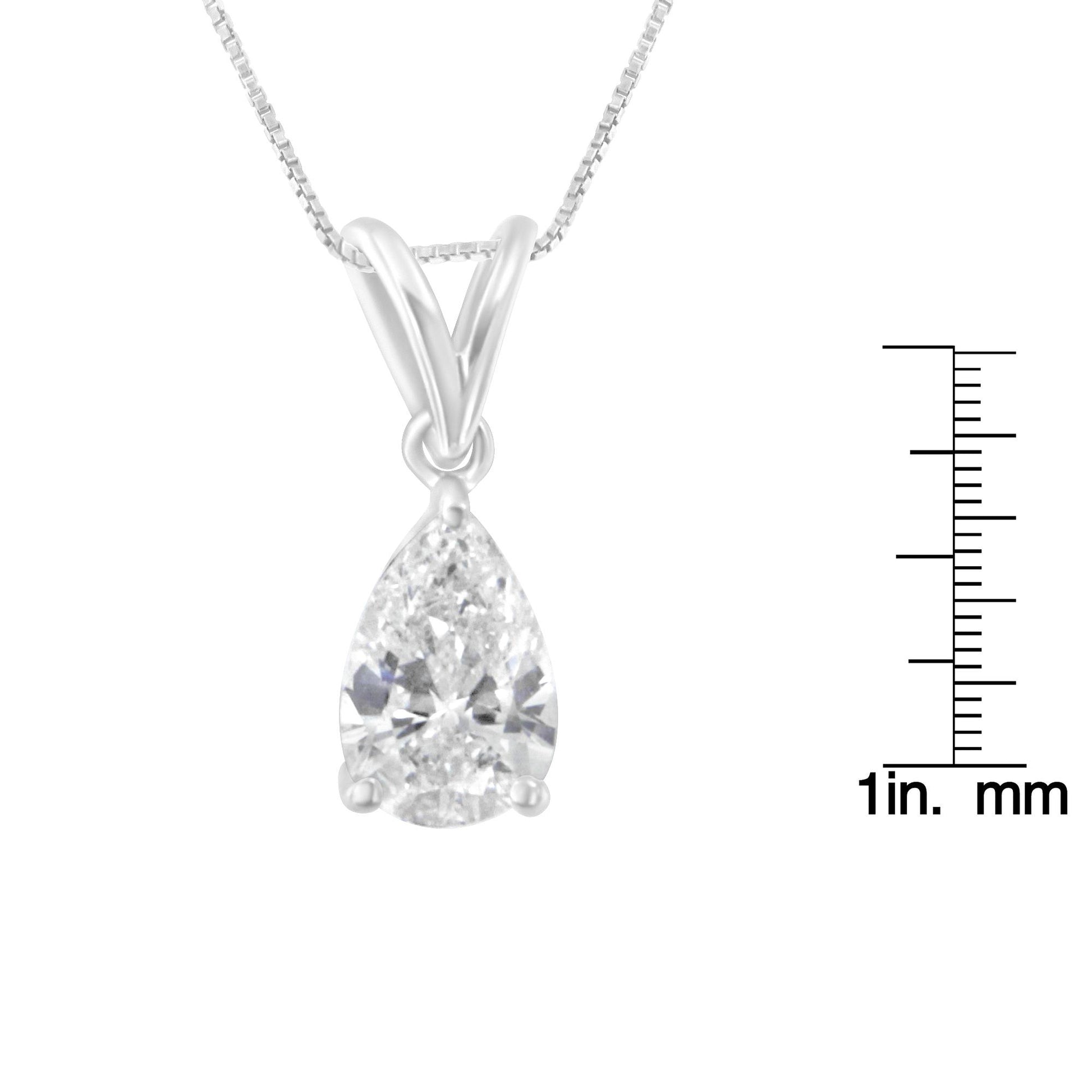 Close-up front view of a white metal necklace with a pear-shaped white gemstone pendant in a prong setting, shown next to a scale for size reference.