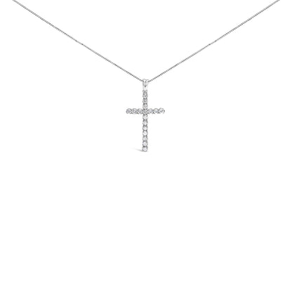 Front facing shot of a white metal necklace with a cross-shaped pendant adorned with round white gemstones in prong settings.