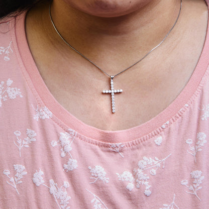 White metal necklace with cross pendant featuring round white gemstones in prong setting, worn on a model, front view.