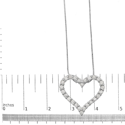Top view of a white metal heart-shaped necklace pendant with round white gemstones in shared prong setting, displayed on a ruler for size reference.